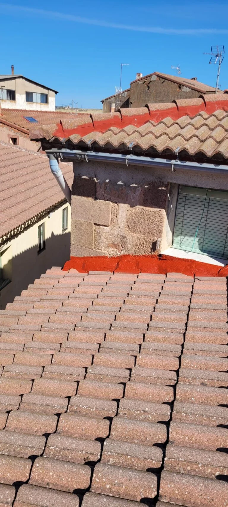 Impermeabilización de remates en tejado de Anguita, con aplicación de sellador rojo en las uniones de tejas